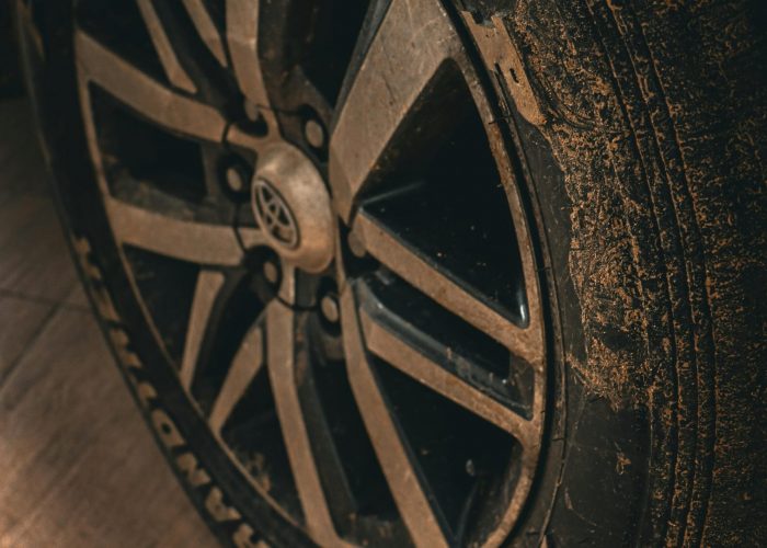 A detailed close-up of a dirty car tire on a Toyota vehicle.